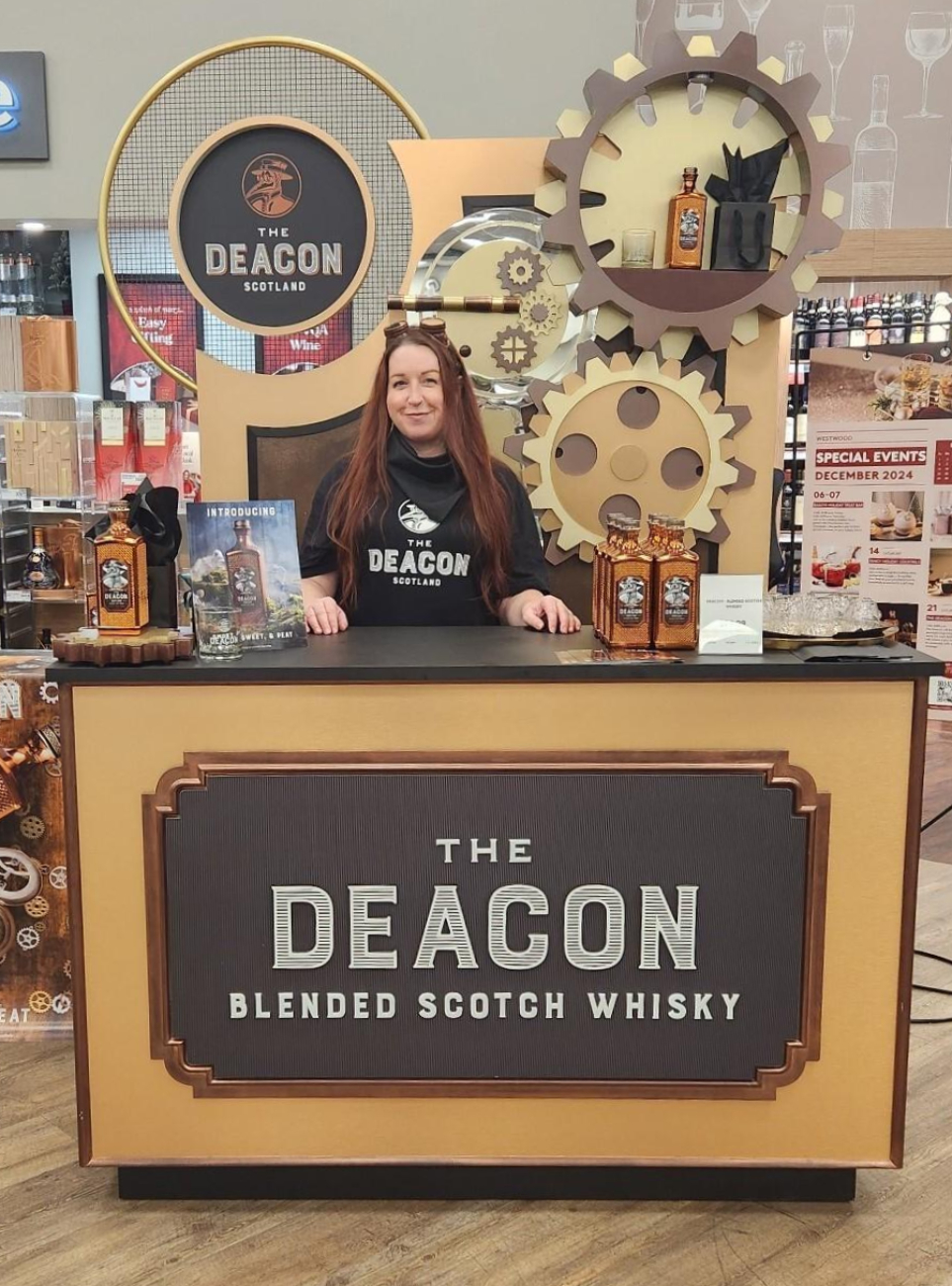 Brand ambassador at a Glenlivet whisky sampling table, showcasing premium whisky bottles and branded materials in a sleek setup.